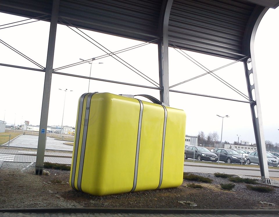 Una valigia gialla sotto una copertura metallica all'esterno dell'aeroporto di Poznań