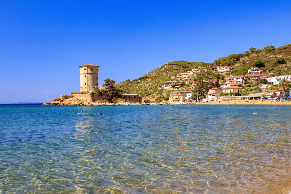 La torre del Campese su uno sperone roccioso, con la riva bassa e le case dell'isola del Giglio
