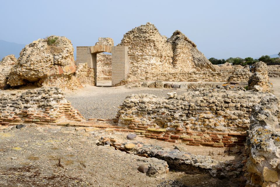 Murature in pietra e laterizio e un passaggio ad arco nell’area archeologica di Nora