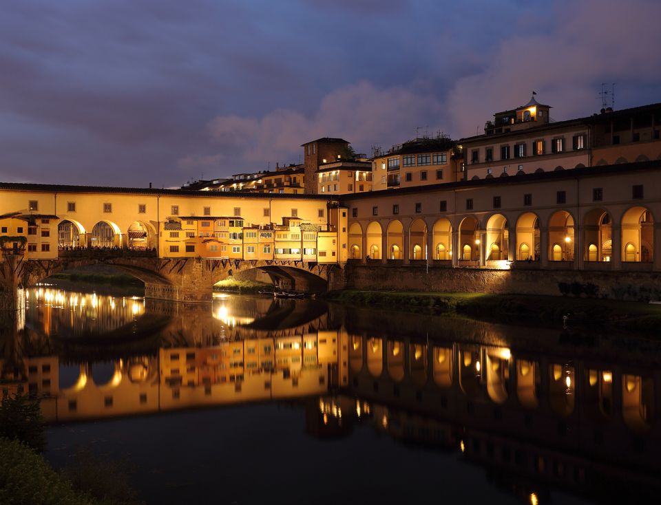 Ponte Vecchio a Firenze al crepuscolo, con gli edifici e le luci riflessi nell'Arno